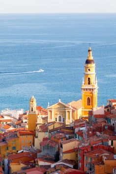 an aerial view of a city with red rooftops and blue water in the background