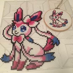 a cross stitch pattern with a pink and blue bunny on it next to a hoop