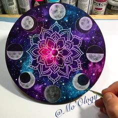 a person is holding a paintbrush in front of a paper plate with the moon phases painted on it