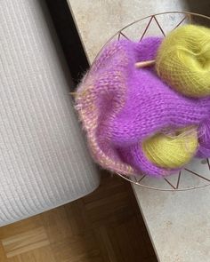 a purple and yellow knitted object in a wire basket on a white table top