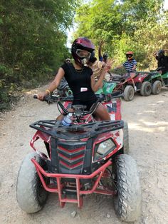 two people riding four wheelers on a dirt road