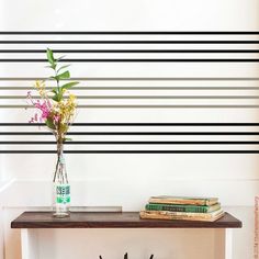 a vase with flowers on top of a table next to books and a book shelf