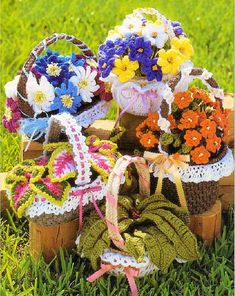 several crocheted baskets with flowers in them on the grass next to each other