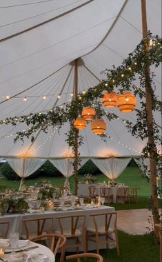 an outdoor tent with tables and chairs set up for a wedding reception in the evening