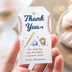 a person holding up a thank you tag with baseballs and bats on it in front of a cake