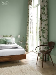 a bed sitting in a bedroom next to a window with green walls and white carpet