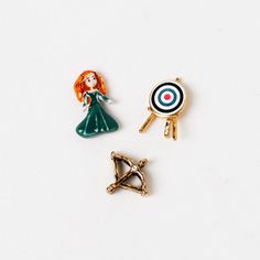 three pin badges on a white surface one has a girl, the other is a target