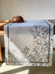 a piece of bread sitting on top of a table next to a white cloth with yellow flowers