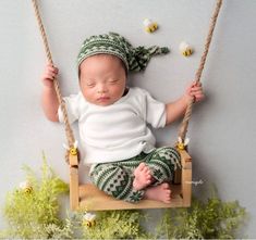 a baby is sitting on a swing with his eyes closed and head turned to the side