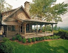 a log cabin with a porch and covered veranda in the front yard is surrounded by lush greenery