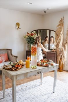 two women standing in front of a table with food on it