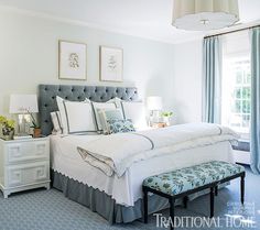 a bedroom with blue and white bedding, two nightstands and pictures on the wall