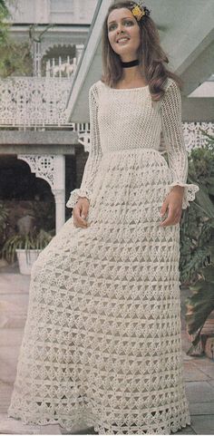 a woman in a white crocheted dress posing for the camera with her hand on her hip