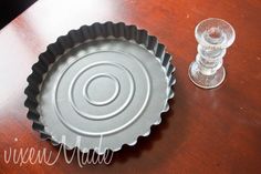 an empty pan sitting on top of a wooden table next to a wine glass and salt shaker