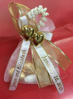 two gold heart shaped candies in a clear bag with ribbon and bow on top