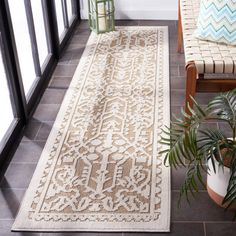 a rug on the floor next to a chair and potted plant in front of a window