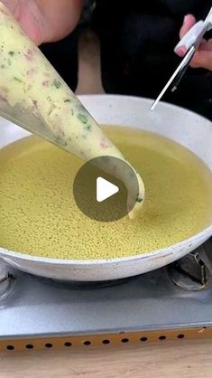 a person is using a knife to cut something into a bowl with liquid in it