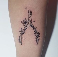 a tattoo on the leg of a woman with scissors and flowers around her legs,