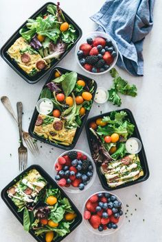 four plastic trays filled with different types of food on top of a white table