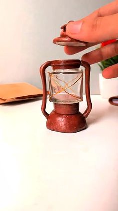 a person is holding a small lantern on a table