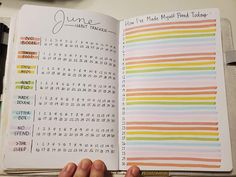 someone is holding an open planner book in their left hand and the pages are lined with colorful stripes