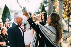 a bride and groom are holding their hands up in the air as they look at each other