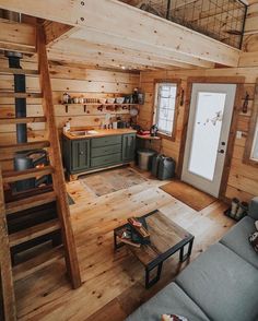 a living room filled with furniture next to a kitchen and dining area in a log cabin