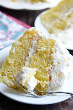 a piece of cake with white frosting on a plate and fork in front of it