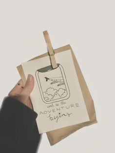 a person holding up a paper bag with an image of a plane on it and the words adventure written in black ink