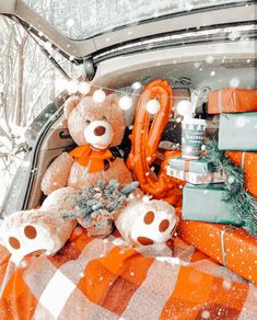 a teddy bear sitting in the back of a car with christmas presents on it's trunk