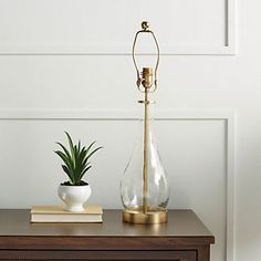 a table with a lamp, potted plant and book on it