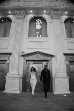 black and white photo of bride and groom in front of the doors of an old building