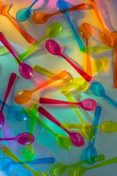 many colorful spoons are arranged on a white surface