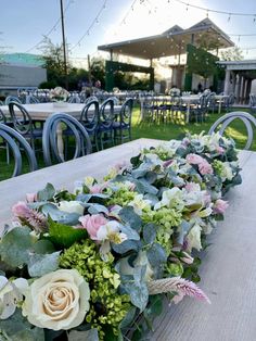 a long table topped with lots of flowers and greenery on top of wooden tables