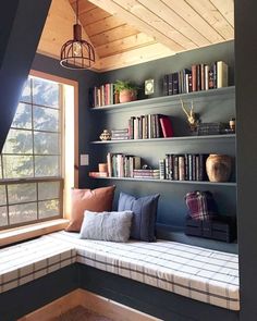 a window seat in the corner of a room with bookshelves and shelves full of books