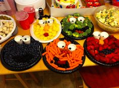 a table topped with plates filled with fruit and veggies covered in googly eyes