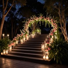 candles are lit on the steps leading up to an archway with flowers and greenery