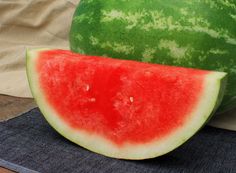 a slice of watermelon sitting on top of a cutting board next to another piece of watermelon