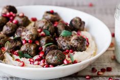 a white bowl filled with meatballs and pomegranate