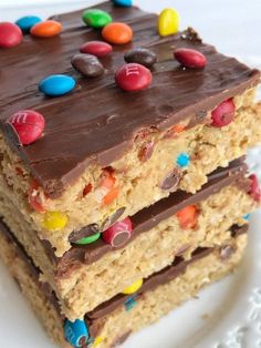 two pieces of cake on a plate with chocolate frosting and m & m candies