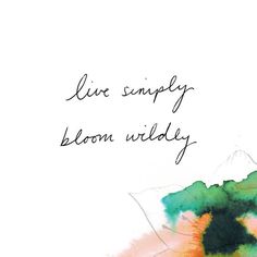 the words live simply bloom wildly are written in black ink on a watercolor background