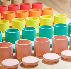 many different colored cups are arranged on a table with circles in the middle and one is empty