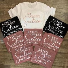 six t - shirts with names on them sitting next to each other in front of a wooden table