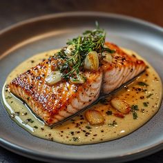 two fish fillets on a plate with sauce and garnishes in it