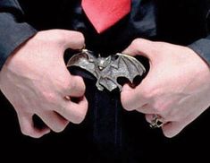 a man wearing a red tie and black suit with a bat ring in his hand