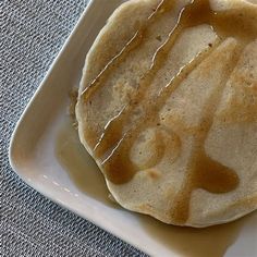 a white plate topped with pancakes covered in syrup