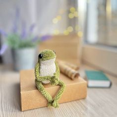 a small stuffed frog sitting on top of a piece of cardboard