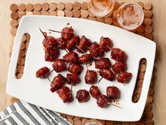 a white tray topped with lots of food on top of a wooden table next to drinks