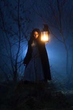 a woman holding a lantern in the woods at night