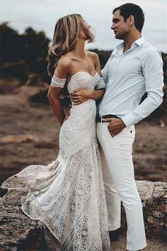 a man and woman standing next to each other on top of a rock covered hillside